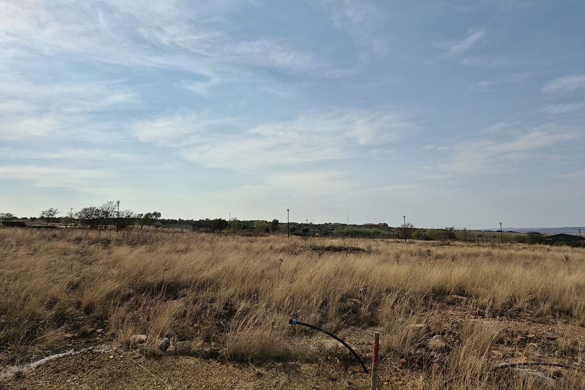 A view of a vacant residential plot featuring dry grass and visible utility connection points, ready for future development.