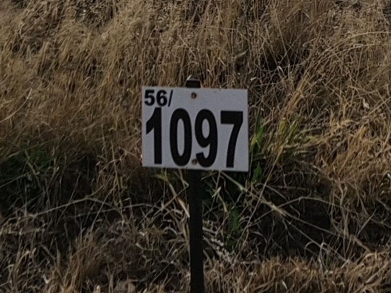 A close-up view of a property identification marker sign on a vacant residential lot.