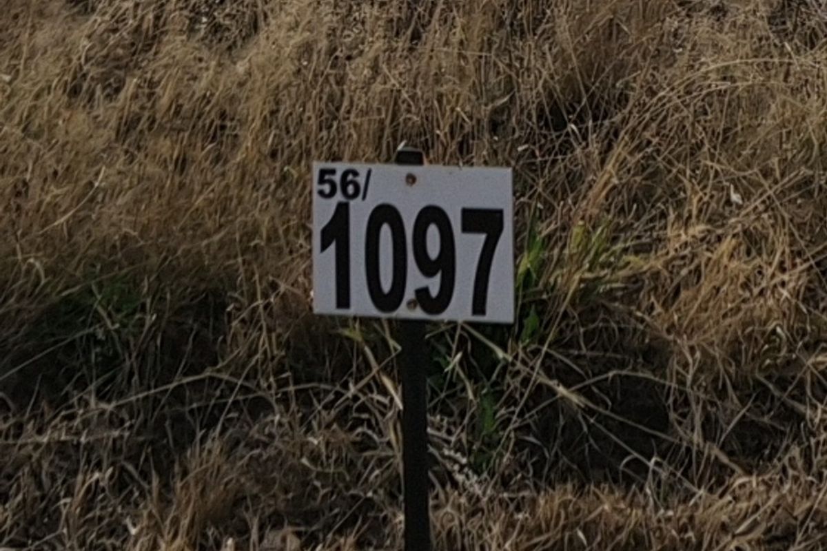 A close-up view of a property identification marker sign on a vacant residential lot.