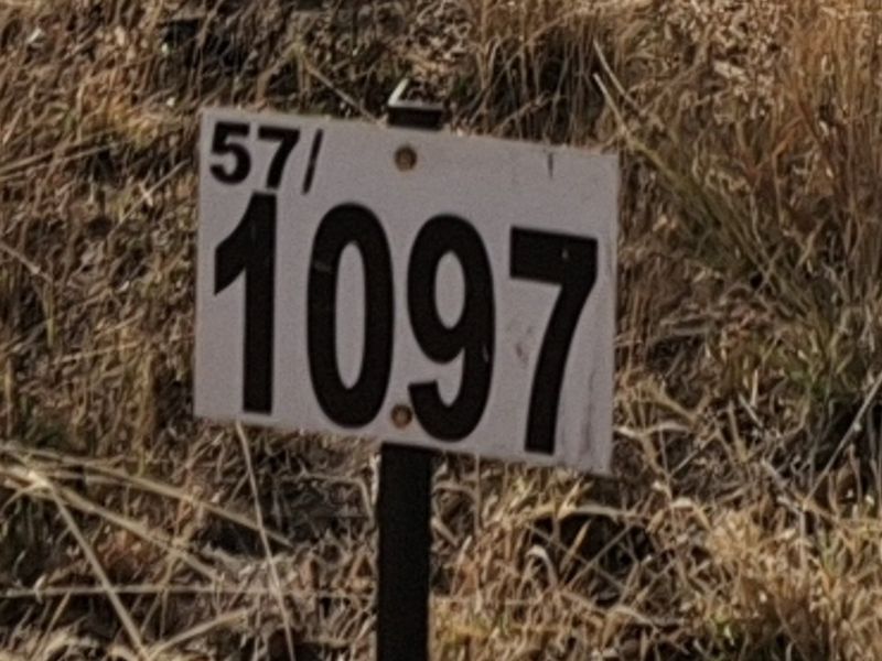 A close-up view of a property identification sign on a vacant residential lot.