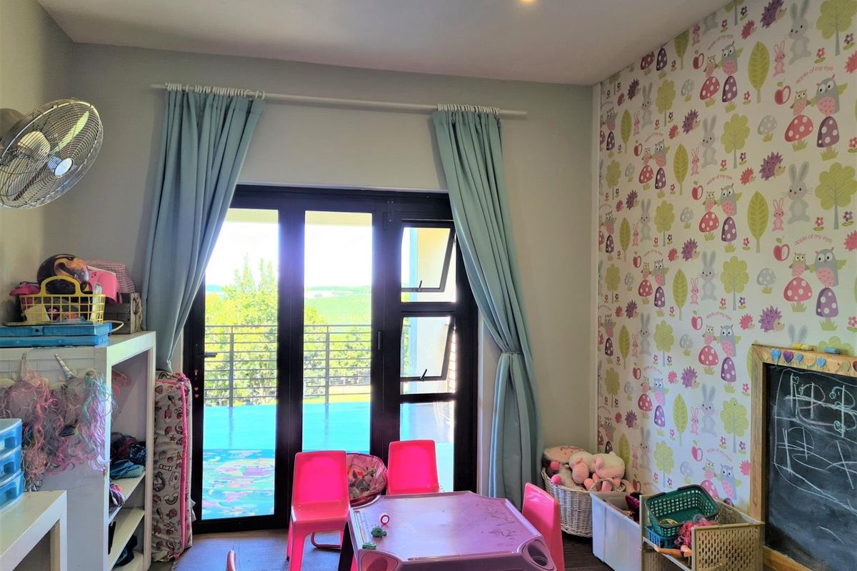 A bedroom featuring patterned wallpaper, recessed ceiling lighting, and dark-framed sliding glass doors that open onto a balcony with scenic views.