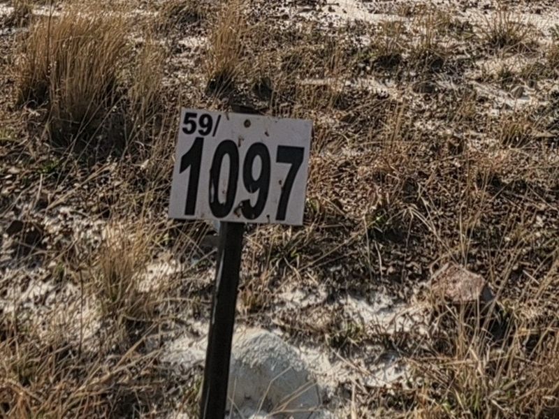A close-up view of a residential property boundary marker post on a vacant plot of land.