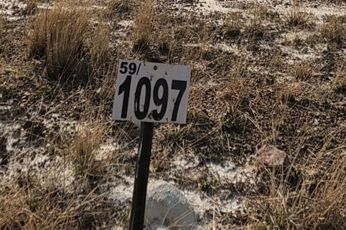 A close-up view of a residential property boundary marker post on a vacant plot of land.