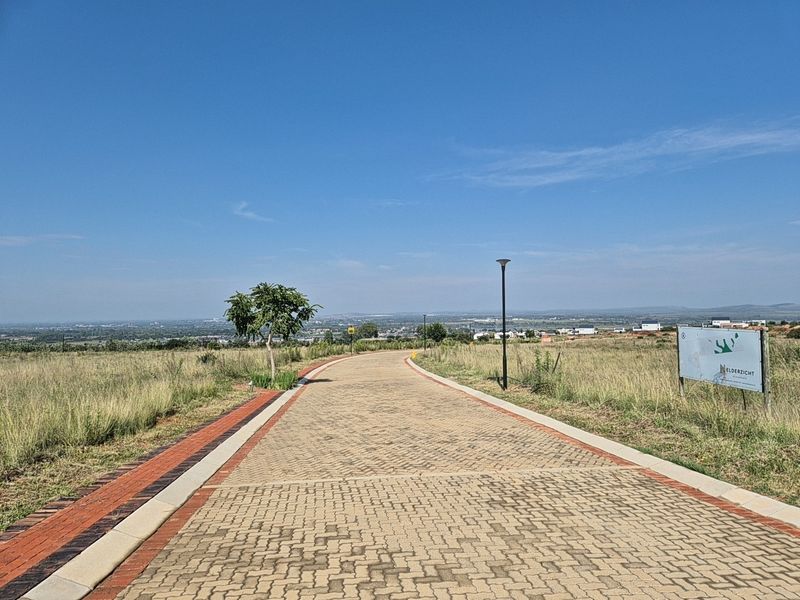 A paved access road within a residential estate, featuring street lighting and clear views of the surrounding landscape.