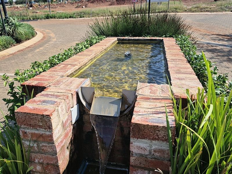 A well-maintained brick water feature and fountain located within a landscaped garden area on a residential property.