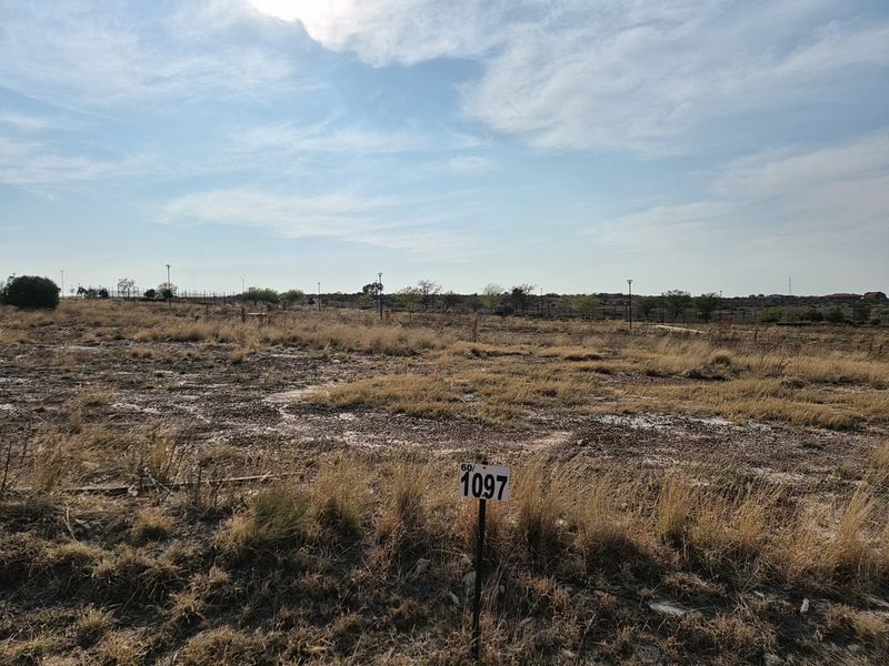 A vacant residential plot of land featuring natural grass coverage and perimeter fencing, ready for development.