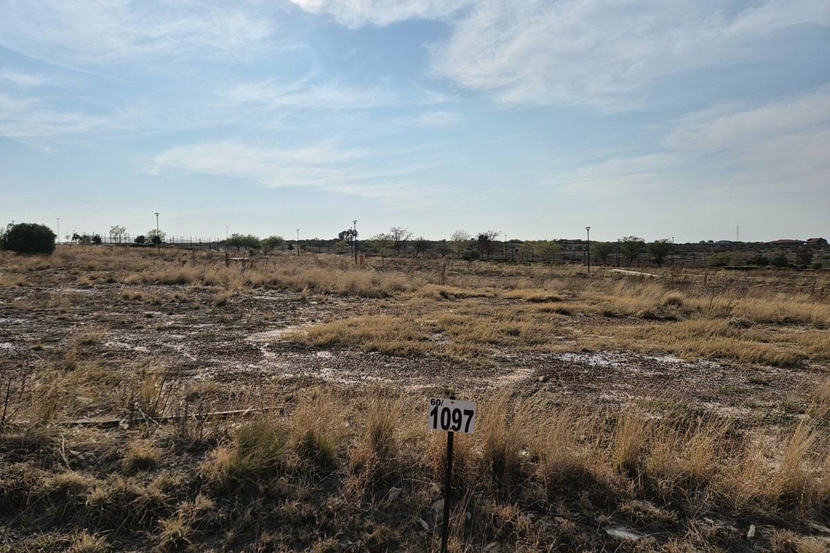 A vacant residential plot of land featuring natural grass coverage and perimeter fencing, ready for development.