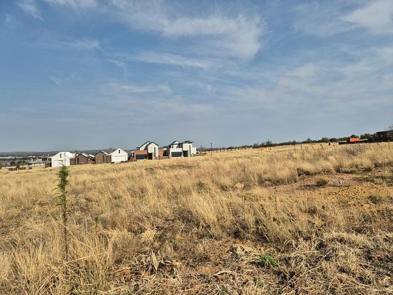 A view of the vacant residential land featuring natural grass terrain with established residential properties visible in the background.