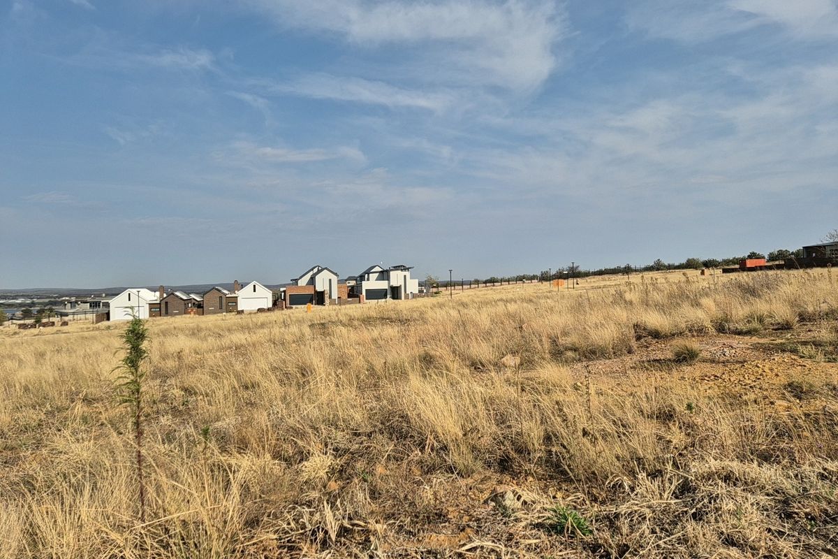 A view of the vacant residential land featuring natural grass terrain with established residential properties visible in the background.