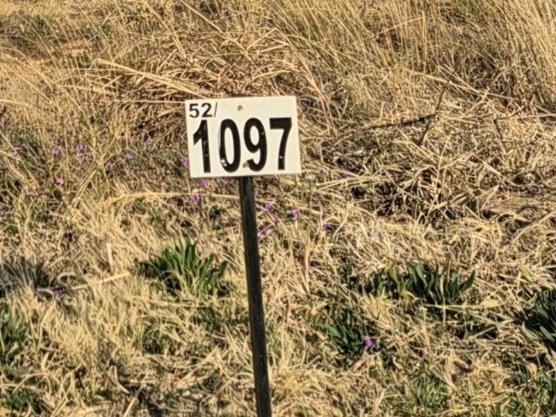 A close-up view of a property boundary marker stake indicating the plot number on a vacant residential lot.