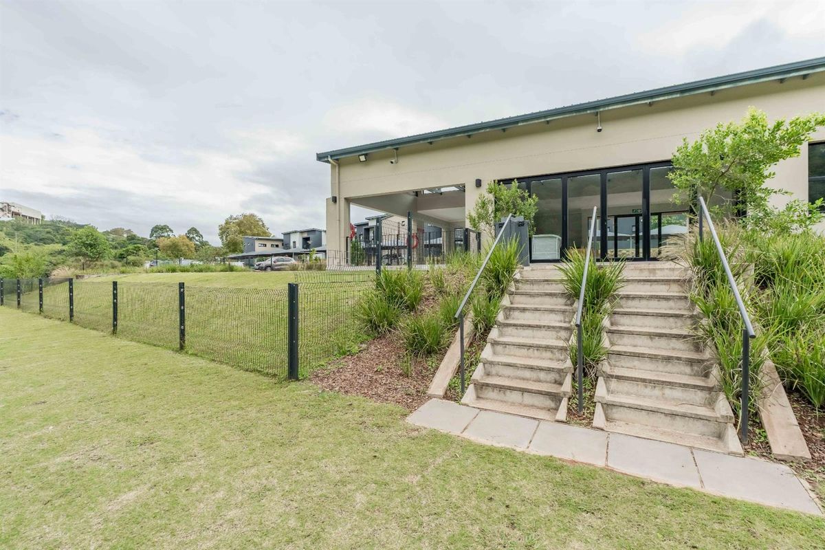 Exterior view of the property featuring a landscaped lawn, concrete staircase with metal railings, and a covered patio area with glass sliding doors.