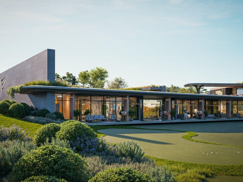 A modern clubhouse facility featuring expansive glass facades, integrated landscaping, and direct access to a manicured putting green.