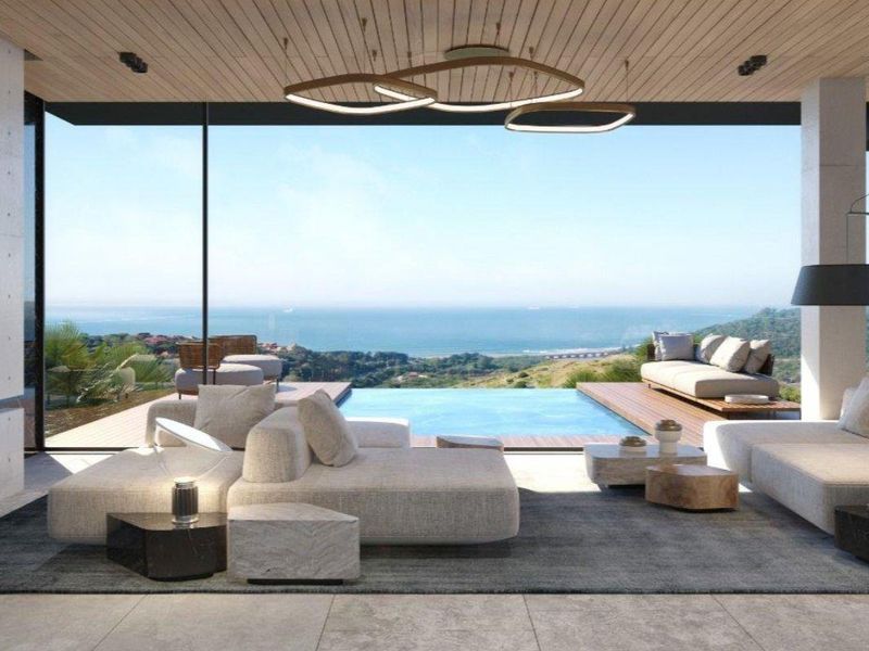Modern open-plan living area featuring floor-to-ceiling glass doors, timber-clad ceiling, and seamless transition to an outdoor deck with a private swimming pool and ocean views.
