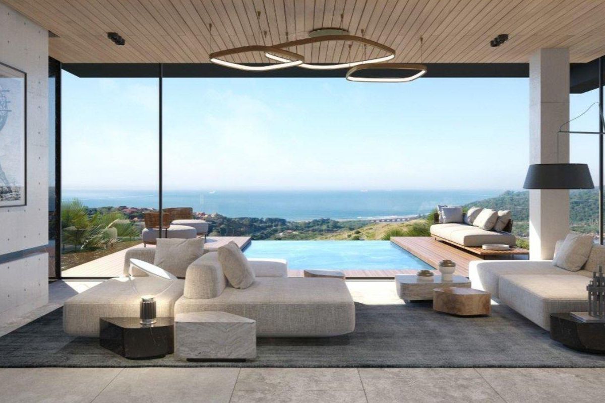 Modern open-plan living area featuring floor-to-ceiling glass doors, timber-clad ceiling, and seamless transition to an outdoor deck with a private swimming pool and ocean views.