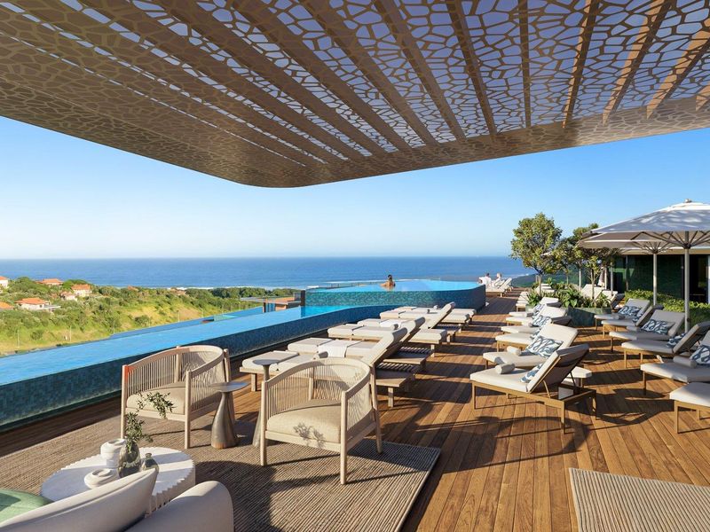 A luxury outdoor pool deck featuring an infinity pool, timber decking, and a decorative overhead canopy with panoramic coastal views.