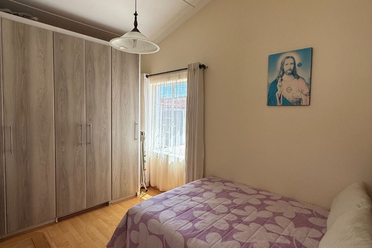A bedroom featuring built-in wooden cabinetry, laminate flooring, and a vaulted ceiling with a pendant light fixture.