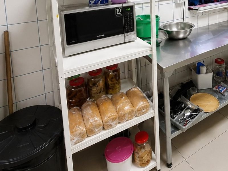 A functional commercial kitchen area featuring tiled walls, tiled flooring, and a stainless steel preparation table for food service operations.