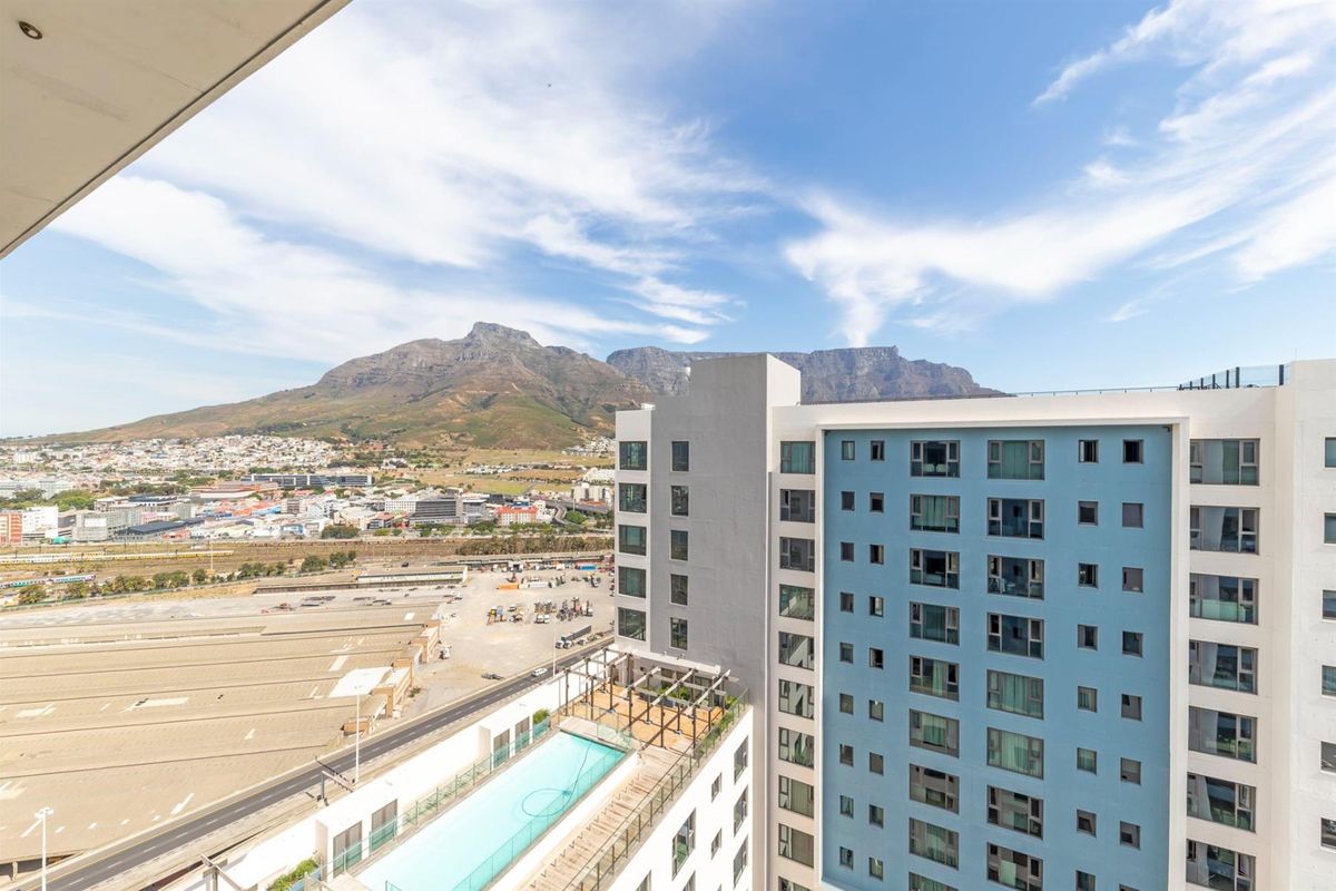 Aerial view of the apartment complex featuring a rooftop swimming pool and terrace with scenic mountain and city views.