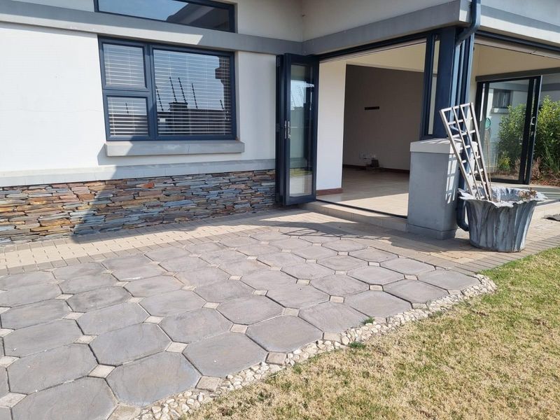 A paved outdoor patio area featuring stone cladding accents and large bi-fold doors leading into the interior living space.