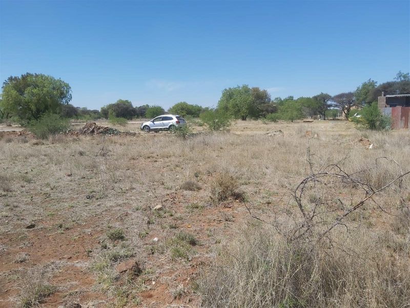 A view of a vacant residential plot featuring natural vegetation and open space, suitable for future development.