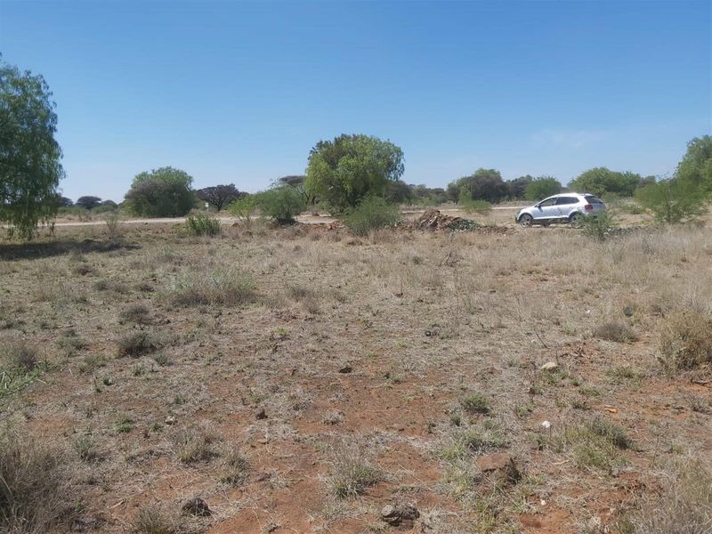 A view of a vacant residential plot featuring natural vegetation and open space, suitable for future development.