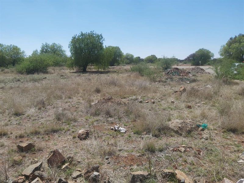 A view of an undeveloped residential vacant land plot featuring native vegetation and rocky terrain.