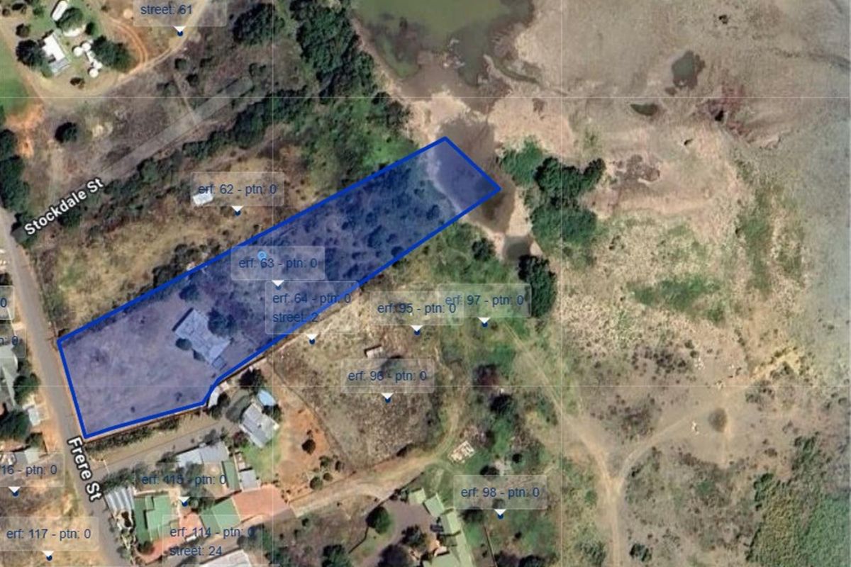 Aerial view of a vacant residential plot outlined in blue, showing its location and proximity to surrounding streets and natural landscape.