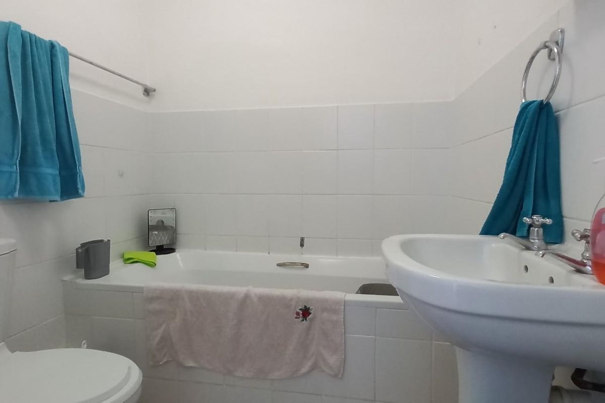 A functional bathroom featuring a white pedestal sink, a standard bathtub with tiled surround, and a toilet.