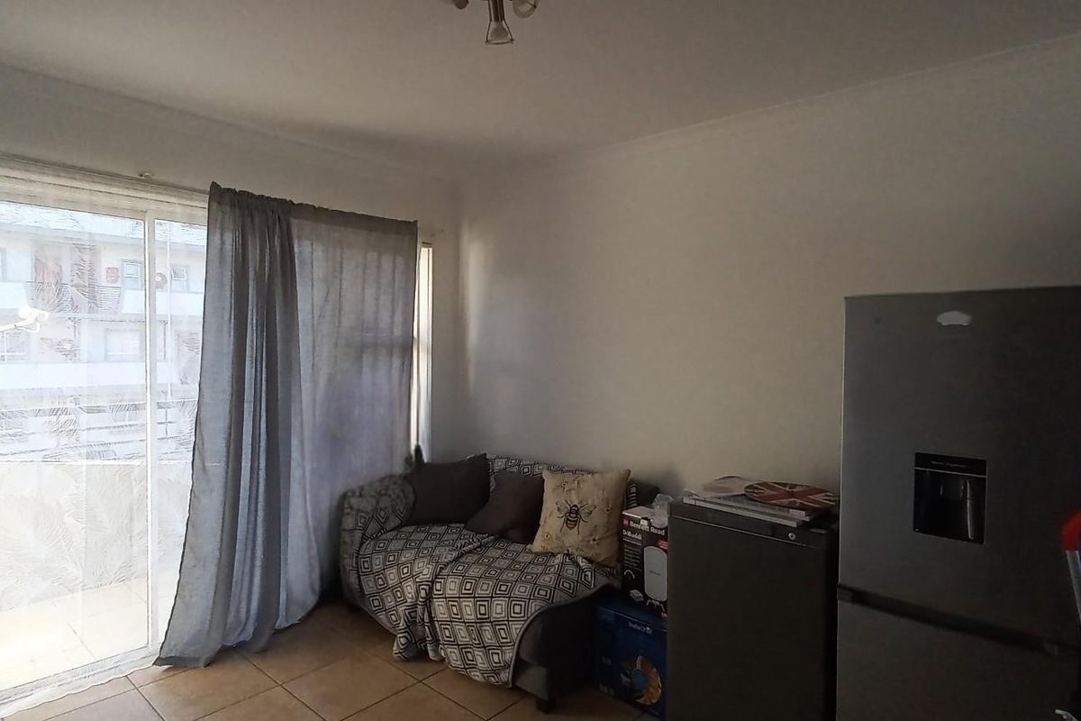 A living area featuring tiled flooring and a large sliding glass door providing access to an outdoor balcony space.