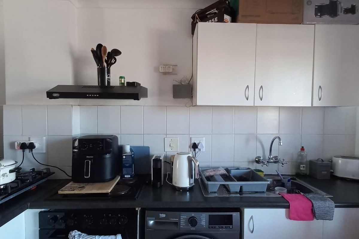 A functional kitchen area featuring built-in cabinetry, a tiled splashback, a sink with mixer tap, and an integrated extractor fan.