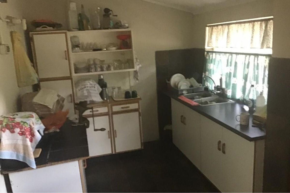 A functional kitchen area featuring built-in cabinetry, a stainless steel sink, and dark countertops, offering a practical layout for food preparation.