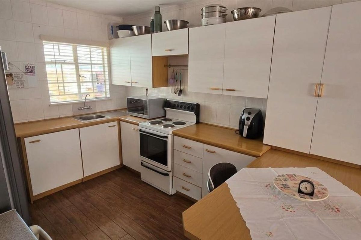 A functional kitchen featuring white cabinetry, wood-look laminate countertops, a built-in oven with hob, and a stainless steel sink.