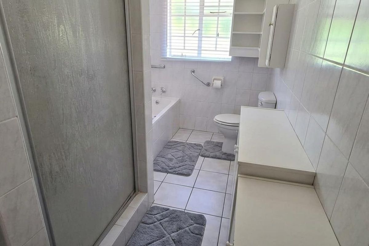 A functional bathroom featuring a built-in bathtub, separate shower enclosure, toilet, and a long vanity unit with storage.