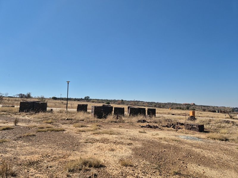 A vacant residential plot featuring dry grass, a street light, and utility infrastructure, ready for development.