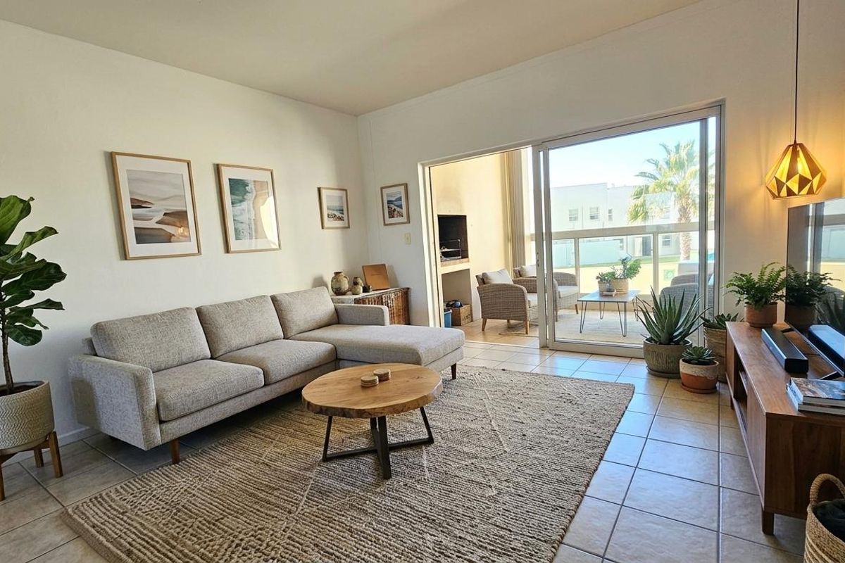 Bright living room featuring tiled flooring and large sliding glass doors that open onto a covered patio area.