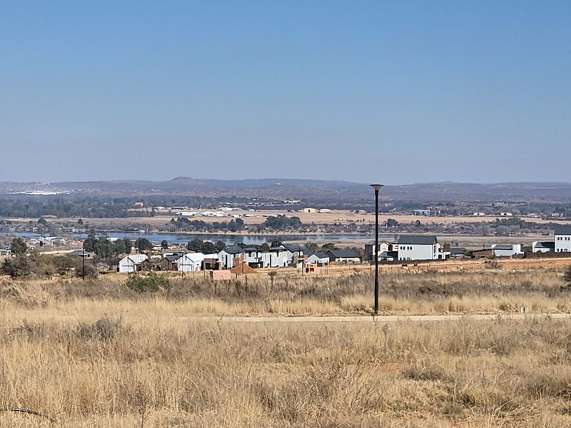 A wide-angle view of the surrounding landscape, featuring open fields, distant residential developments, and a water body under a clear sky.