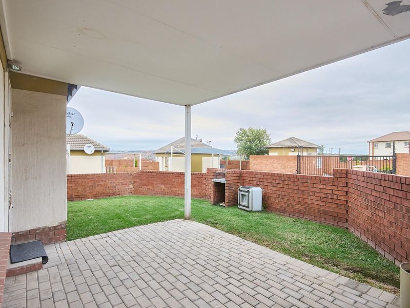 Covered patio area featuring paved flooring, a built-in brick braai, and a private enclosed garden space.