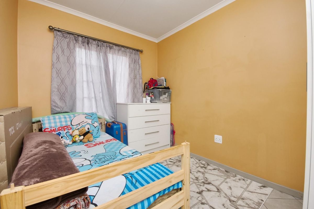 A bedroom featuring tiled flooring and a window with curtain rod, providing a functional space for rest.