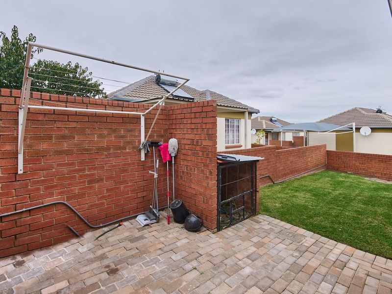A private rear garden featuring a paved patio area, a brick boundary wall, and a wall-mounted fold-down clothes drying rack.