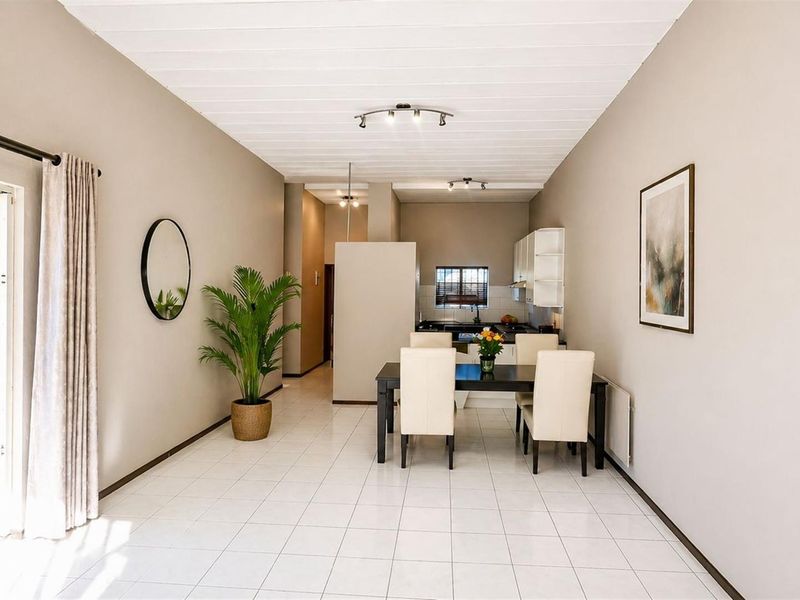 Open-plan living and dining area featuring tiled flooring, neutral walls, and direct access to an outdoor space through a sliding glass door.