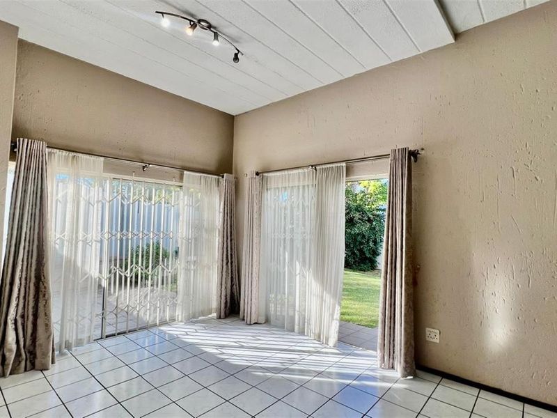 Bright living area featuring tiled floors, track lighting, and dual sliding glass doors providing direct access to the garden.