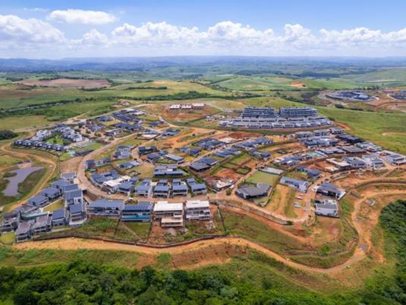 Aerial view of a residential estate development featuring modern homes, paved road networks, and surrounding natural landscape.
