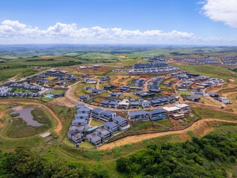 An aerial view of a residential estate development featuring modern housing clusters, paved roads, and surrounding natural landscape.