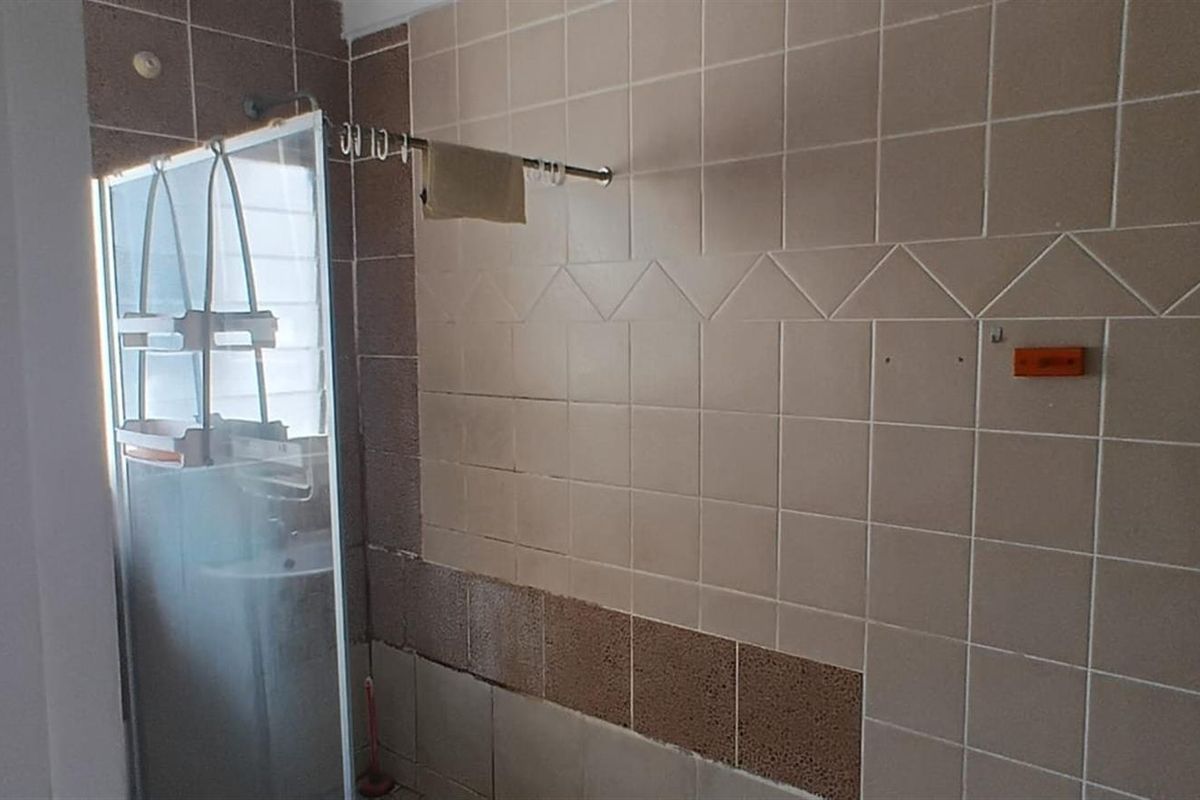 A bathroom featuring a shower enclosure and tiled walls, currently requiring maintenance and cosmetic updates to the tiling.