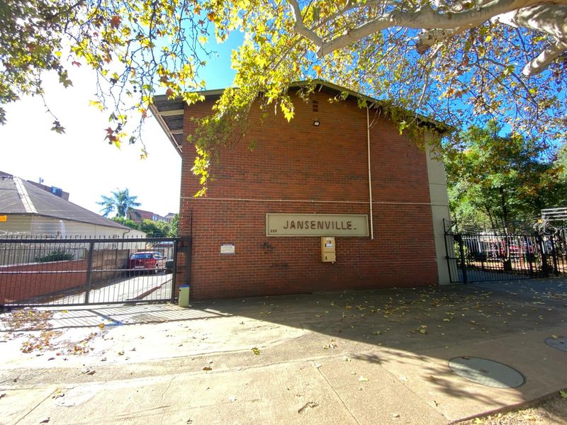 Street-level view of the Jansenville apartment building facade, featuring red brick construction and secure gated access.