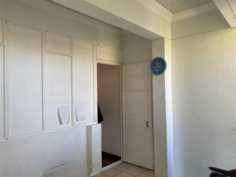 A vacant hallway featuring built-in cabinetry, tiled flooring, and classic cornice detailing, providing a functional transition space within the apartment.