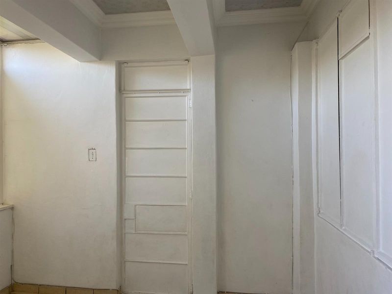 A vacant hallway area featuring a built-in cupboard, coved ceiling details, and neutral white walls, presenting a blank canvas for interior updates.