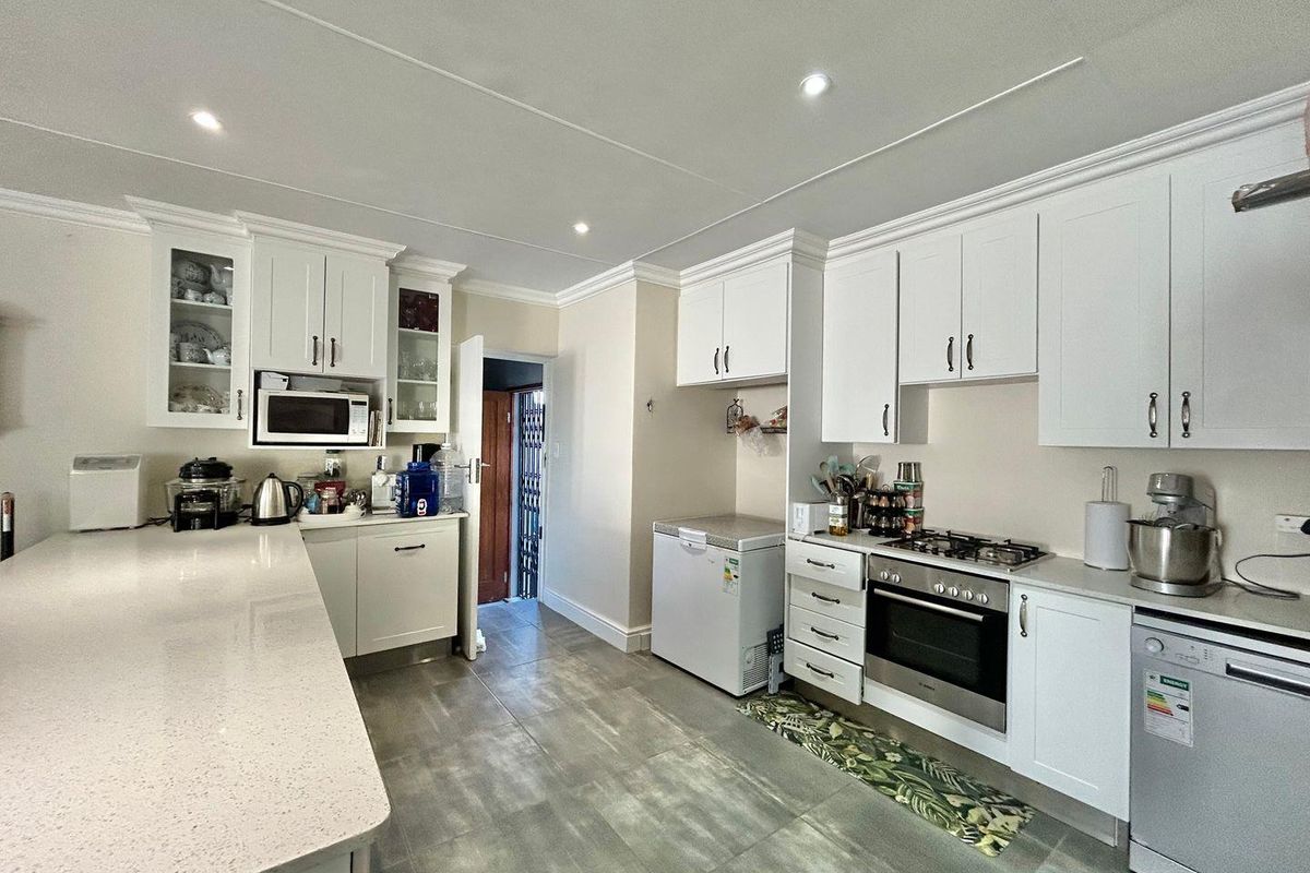 Modern kitchen featuring white cabinetry, stone countertops, integrated oven, gas hob, and tiled flooring with recessed ceiling lighting.