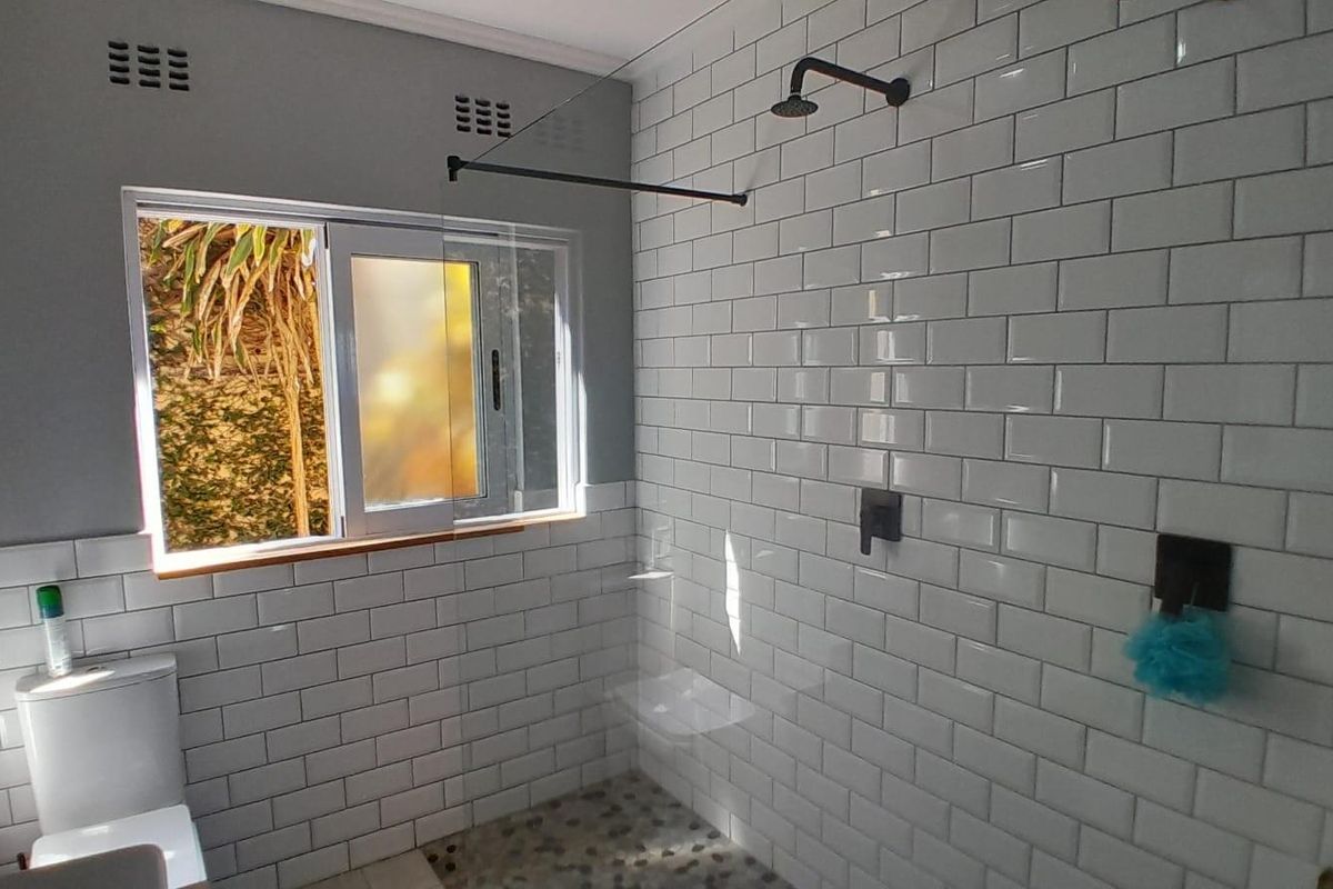 Modern bathroom featuring a walk-in shower with subway tile walls, a glass partition, matte black fixtures, and a window providing natural light.