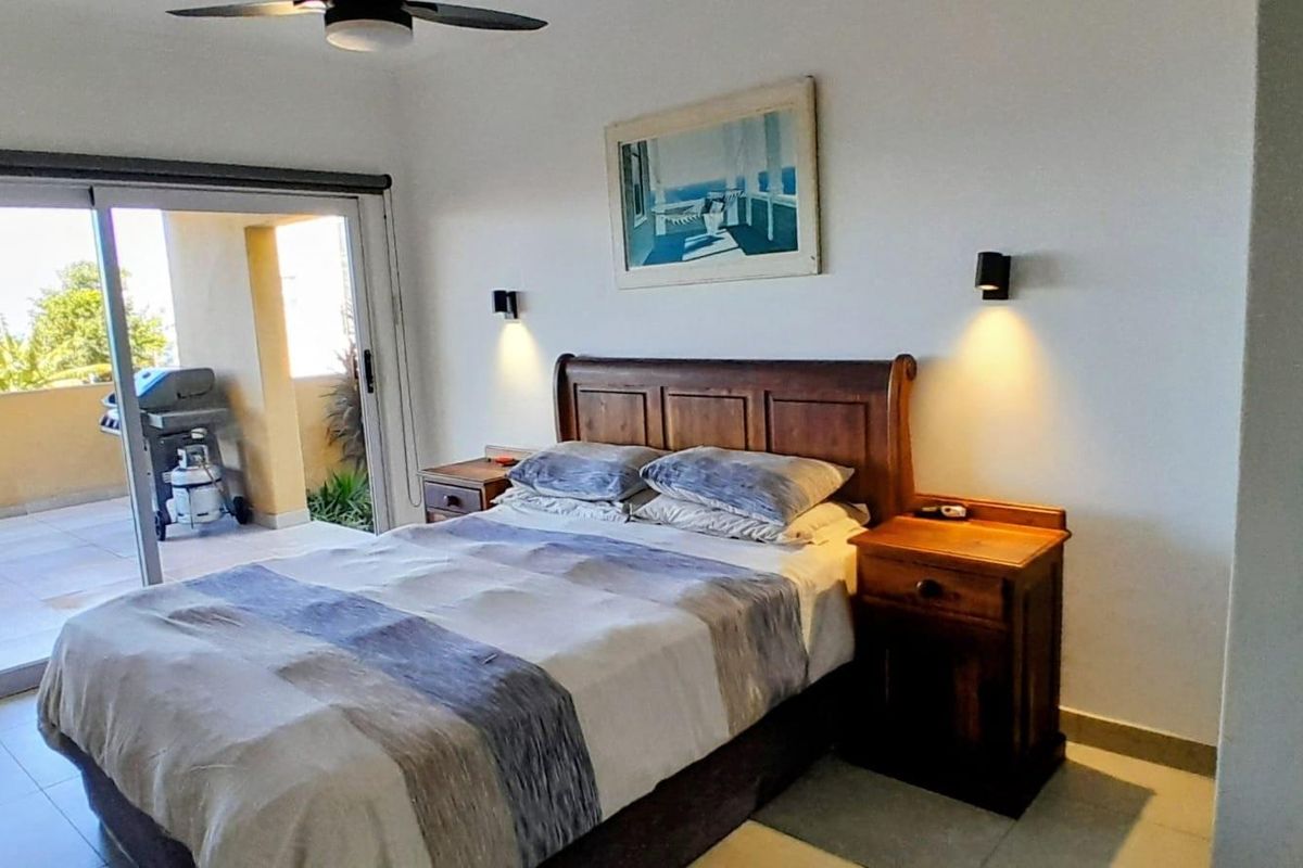 A bedroom featuring a ceiling fan and sliding glass doors that open onto a private balcony.